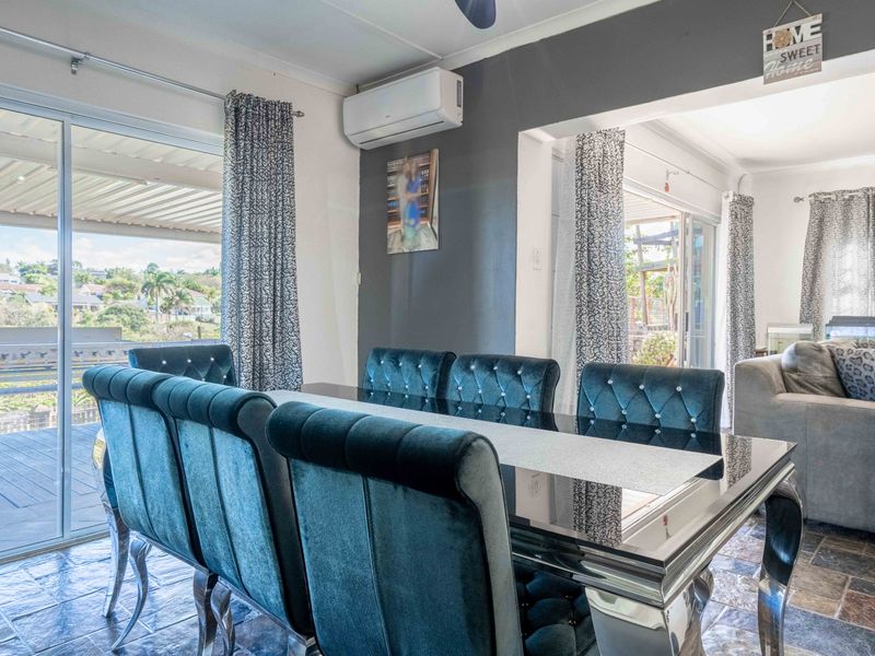 Open-plan living and dining area featuring slate tile flooring, split-system air conditioning, and large sliding glass doors providing access to the outdoor patio.