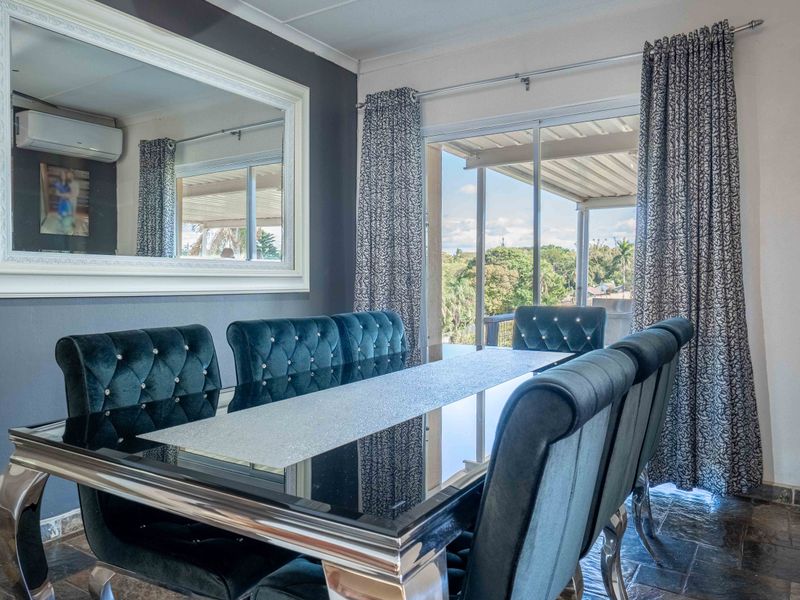 A well-lit dining room featuring slate tile flooring, a split-system air conditioner, and large sliding glass doors providing access to an outdoor area.