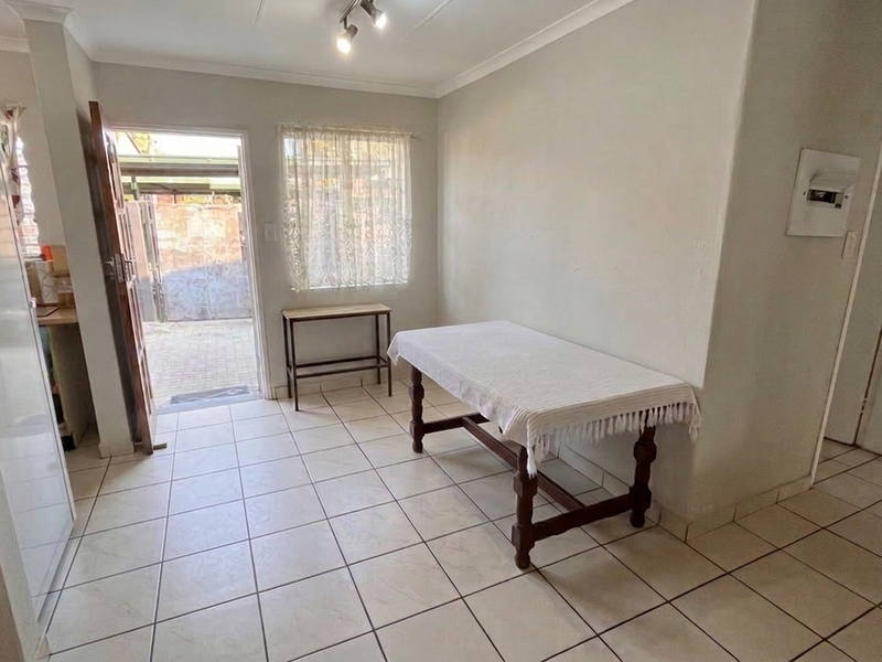 A bright living area featuring ceramic floor tiles, cove cornicing, and direct access to an outdoor patio area.