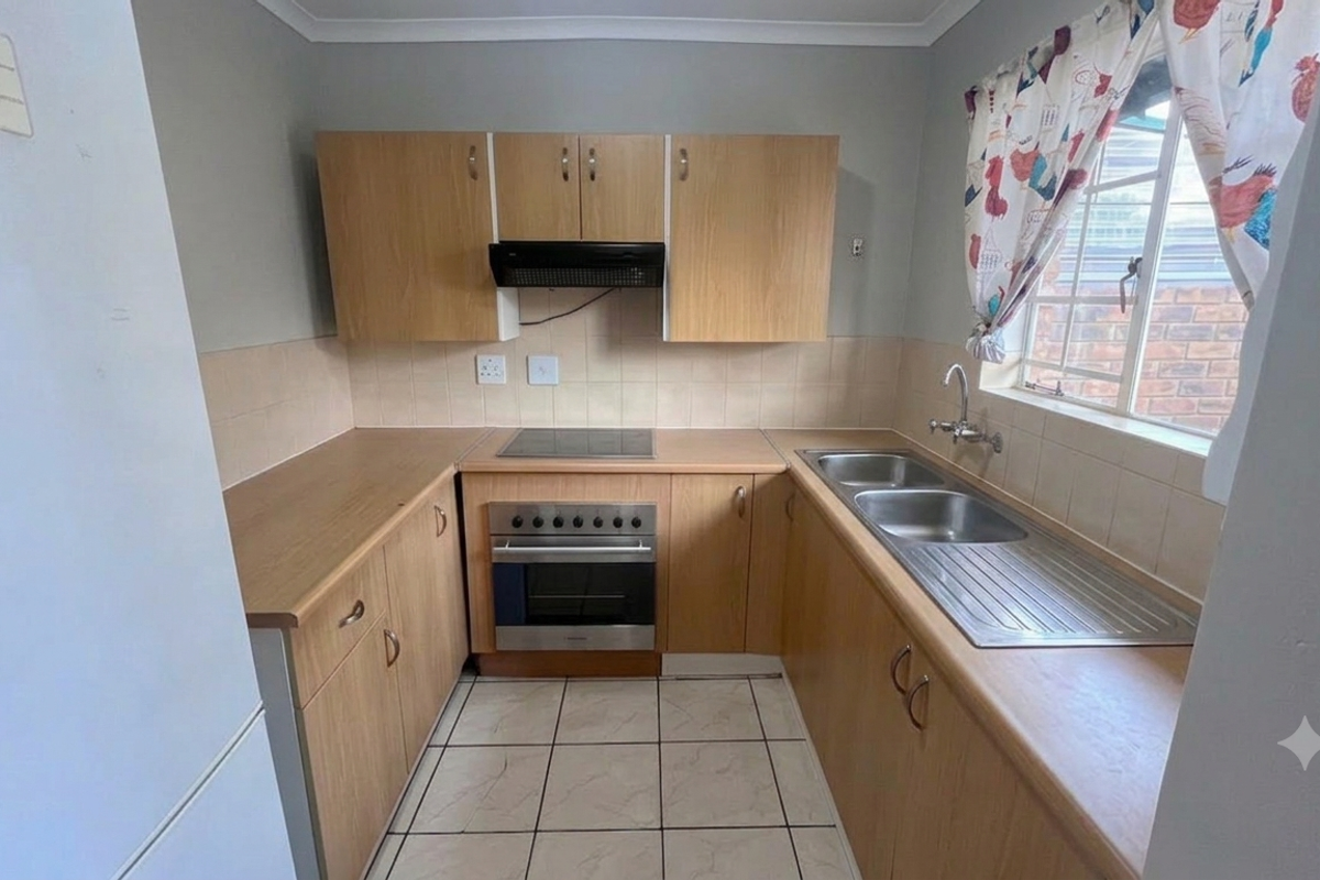 Functional kitchen featuring light wood-finish cabinetry, laminate countertops, built-in oven with hob, and a double stainless steel sink with tiled splashback.