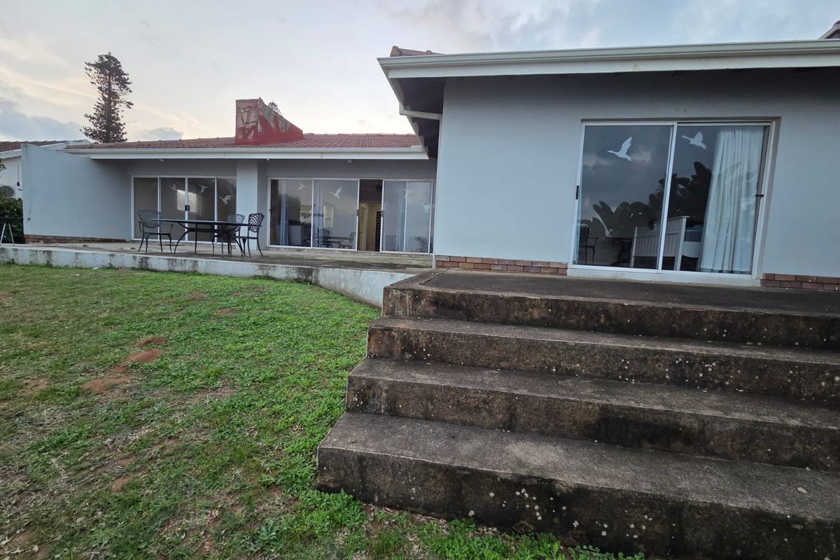 Rear view of the property featuring a concrete patio, sliding glass doors, and exterior stairs leading to the garden area.