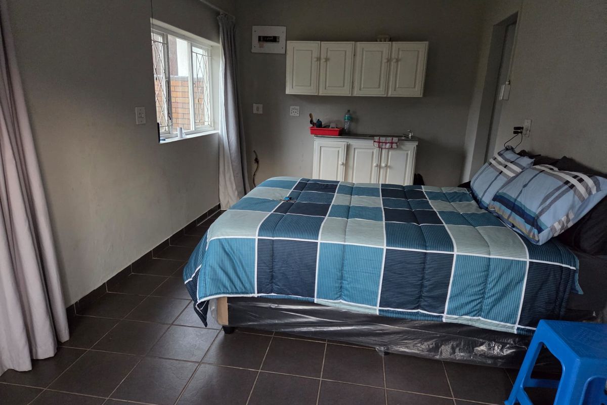 A bedroom featuring tiled flooring, built-in cabinetry with a sink, and an integrated electrical distribution board.