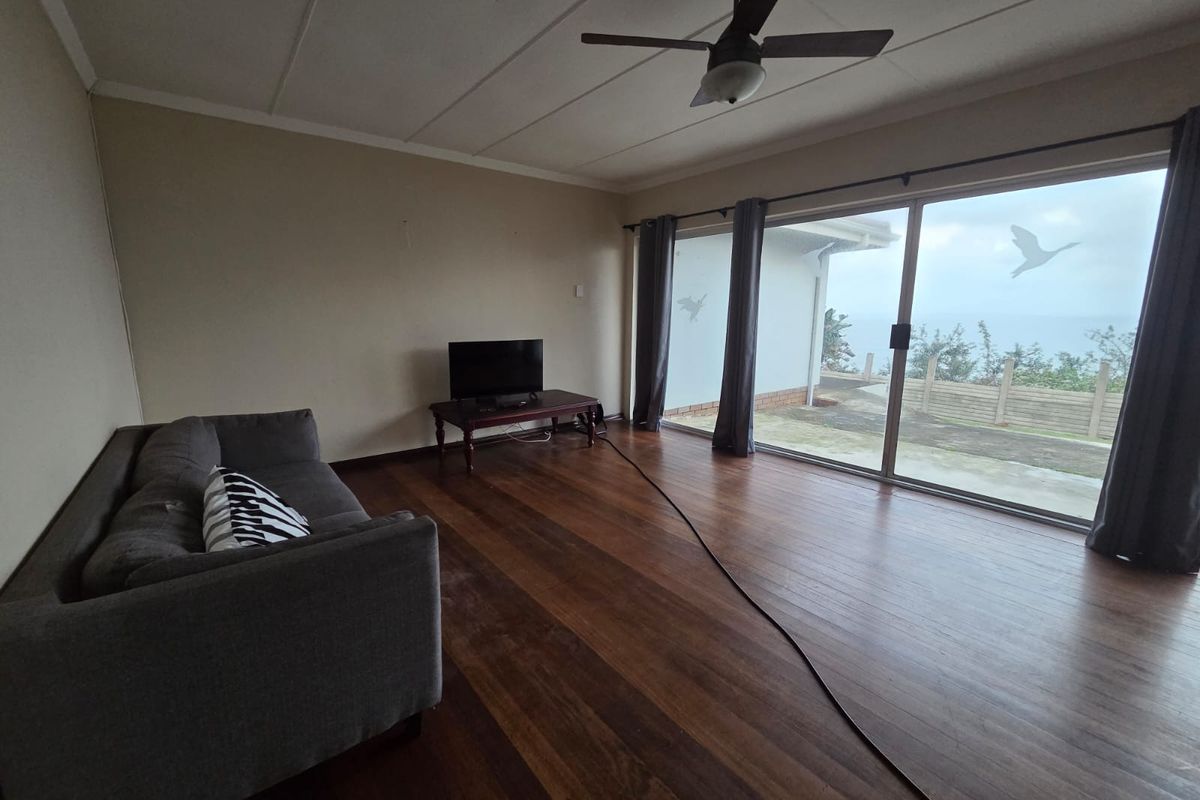 Spacious living room featuring hardwood flooring, a ceiling fan, and large sliding glass doors providing access to the outdoor area.