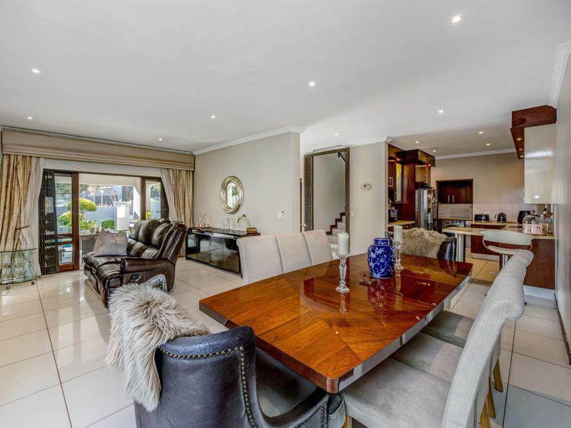 Spacious open-plan living and dining area featuring polished tiled floors, recessed lighting, and seamless flow to the outdoor patio through large sliding glass doors.