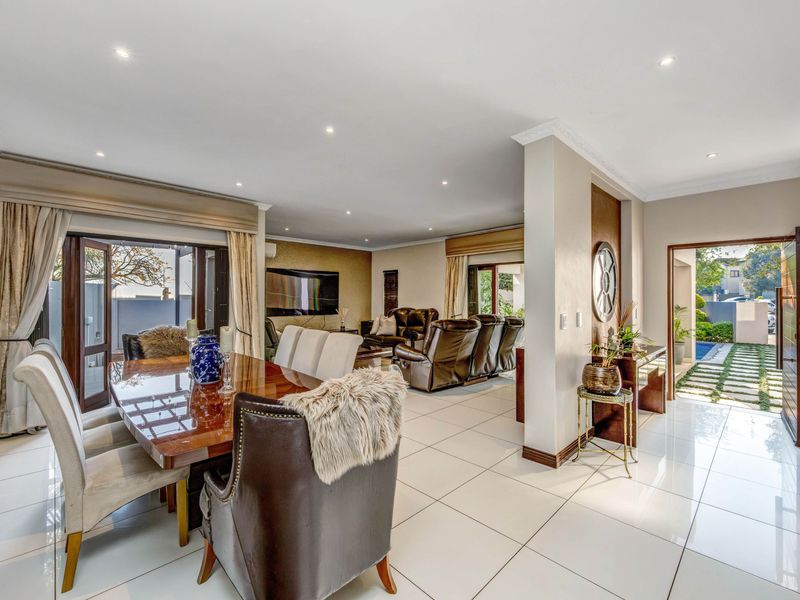 Spacious open-plan living and dining area featuring polished porcelain tiles, recessed lighting, and seamless access to the outdoor patio and garden.