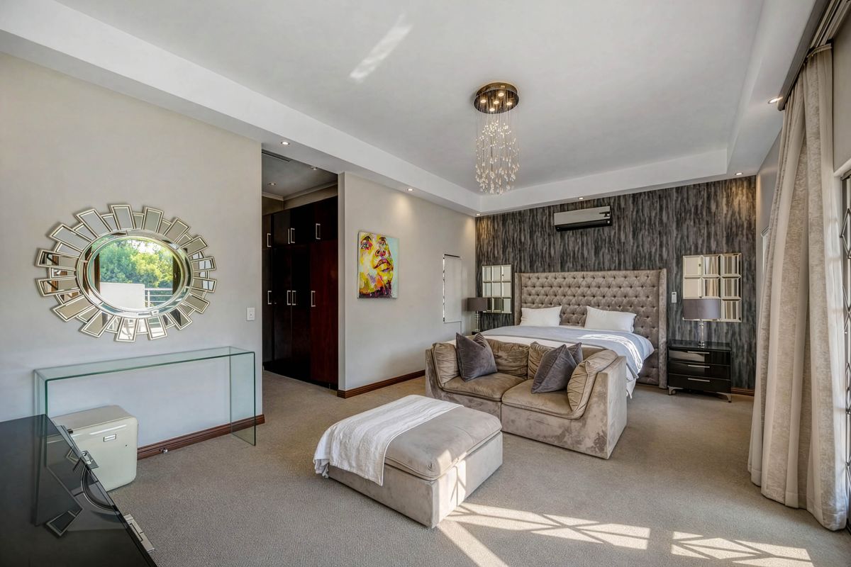 Spacious primary bedroom featuring a tray ceiling, recessed lighting, split-system air conditioning, and integrated built-in cupboards with a modern feature wall.