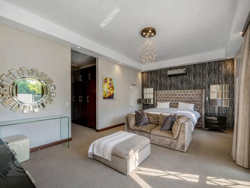 Spacious primary bedroom featuring a tray ceiling, recessed lighting, split-system air conditioning, and integrated built-in cupboards with a modern feature wall.
