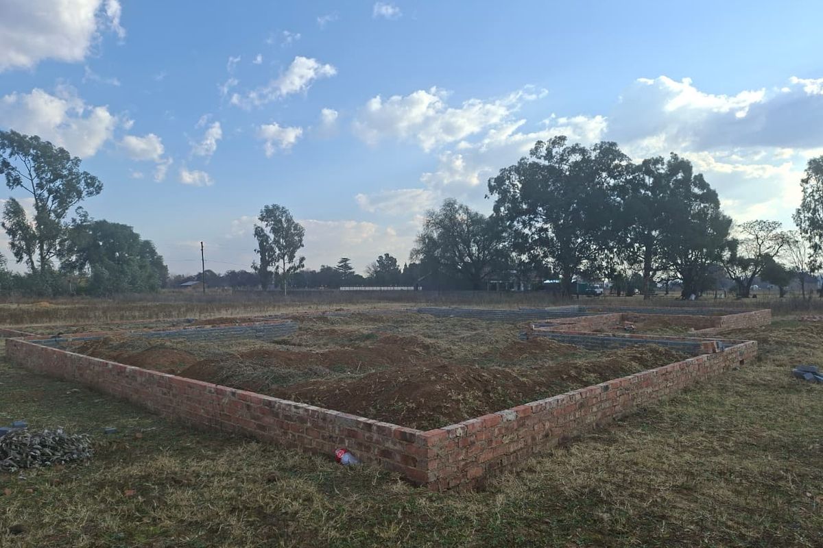 A view of a property under construction, showing the brick foundation and earthwork on a large plot of land.