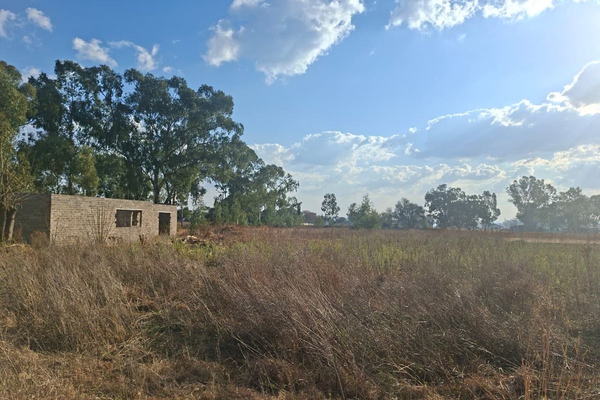 Expansive undeveloped small holding land featuring an incomplete brick outbuilding structure set within a large, overgrown field.