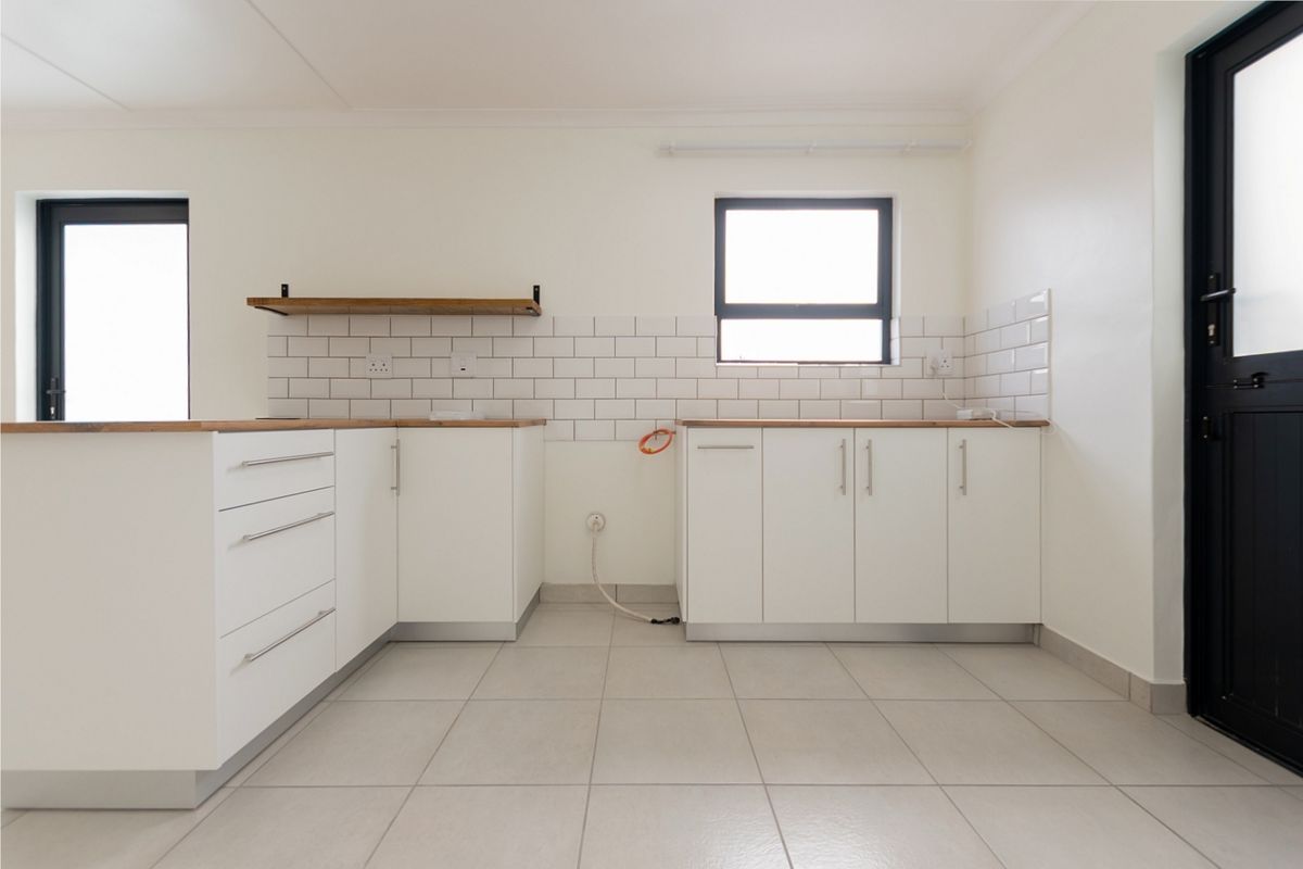 A clean, modern kitchen featuring white cabinetry, wooden countertops, subway tile backsplash, and tiled flooring, ready for appliance installation.