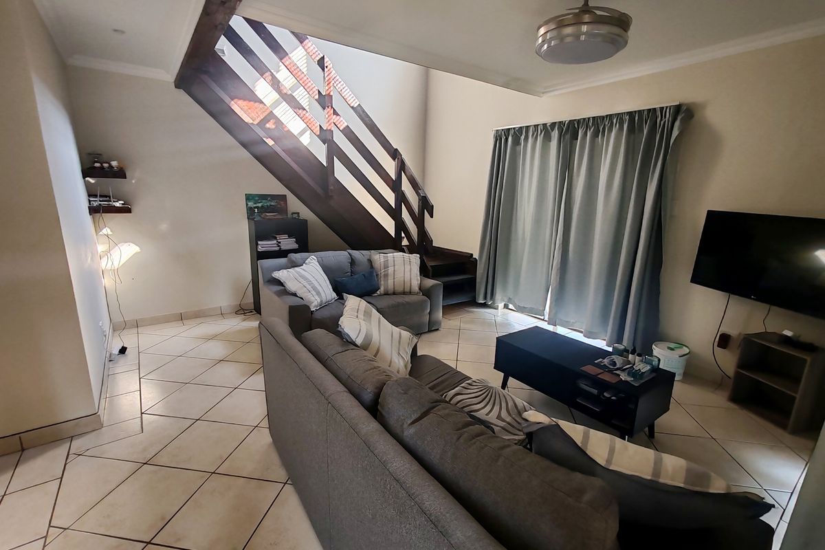 Open-plan living area featuring tiled flooring, a central staircase, and sliding glass doors providing access to the exterior.