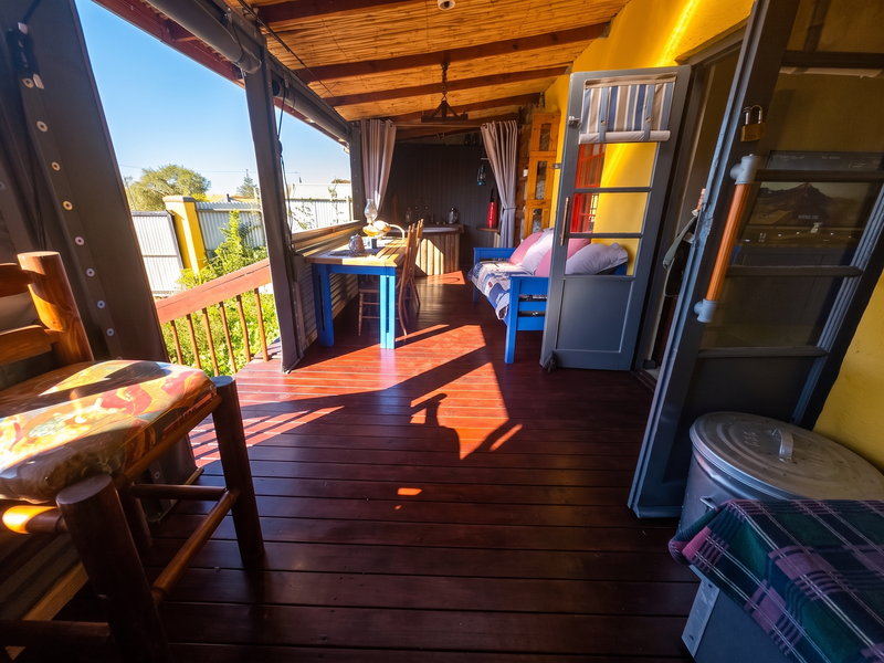 A covered outdoor patio featuring timber decking, a bamboo-lined ceiling, and a built-in sink area, providing a rustic space for outdoor dining and relaxation.