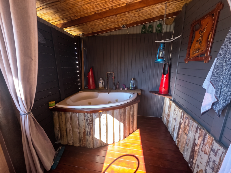 Rustic-style bathroom featuring a corner bathtub with exposed copper plumbing, timber wall cladding, and a bamboo ceiling.