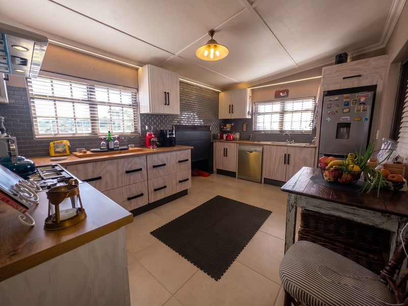 A well-lit kitchen featuring modern cabinetry, a tiled backsplash, integrated appliances, and a functional layout with ample counter space.