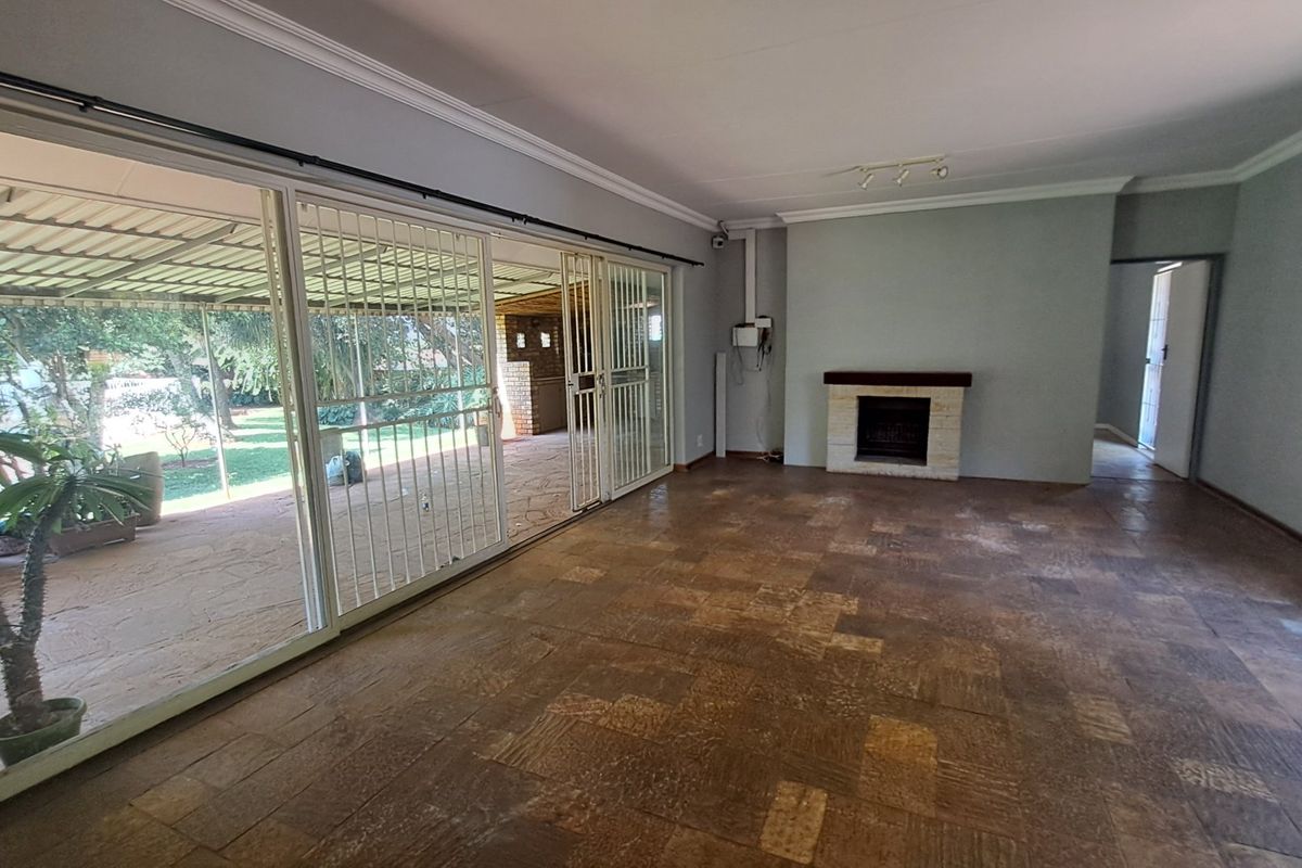 Spacious living room featuring a built-in fireplace, tiled flooring, and large sliding doors providing direct access to the covered patio and garden.