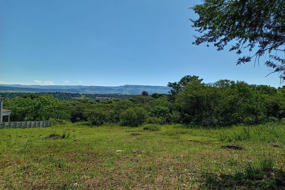 A scenic view overlooking a natural landscape with lush vegetation and distant mountain ranges, showcasing the property's expansive outdoor setting.