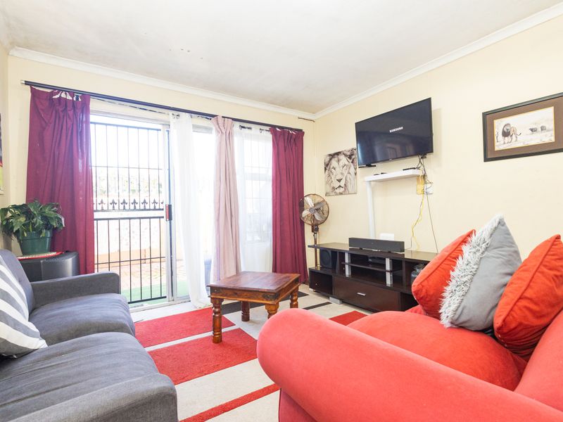 A living room featuring a sliding glass door with security gate access to the exterior, finished with ceiling coving.
