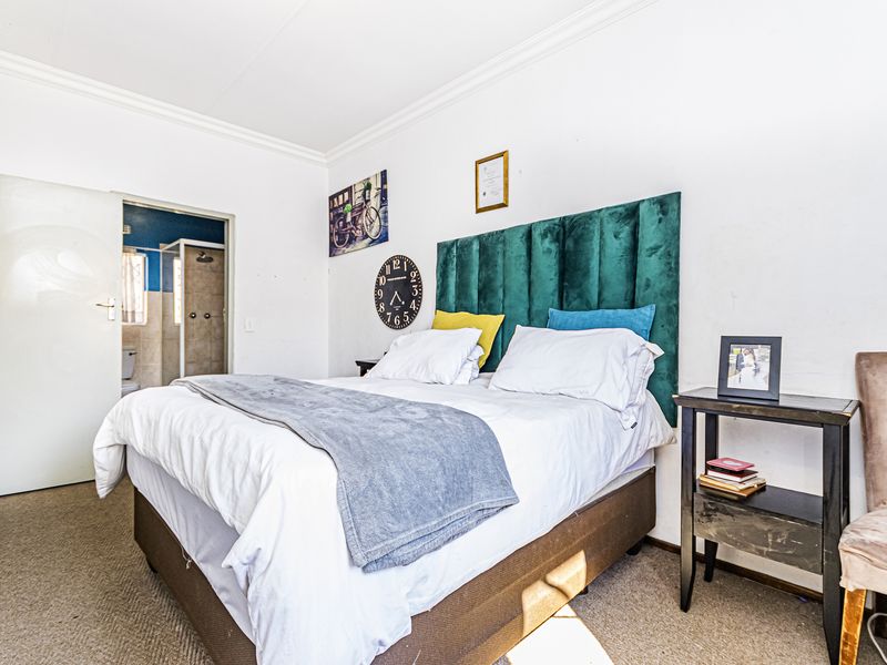A bedroom featuring carpeted flooring, coved ceilings, and direct access to an en-suite bathroom.