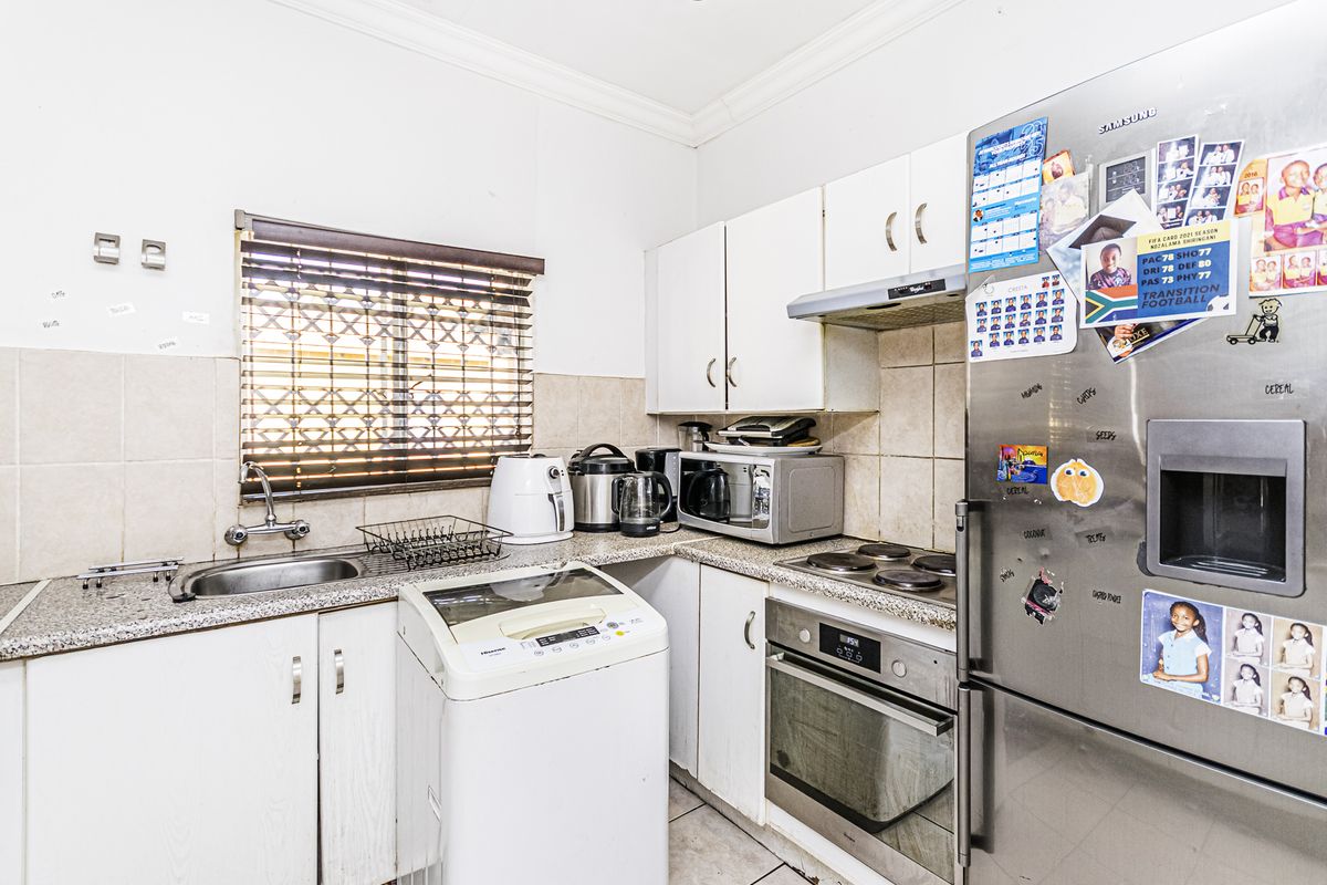 Compact kitchen featuring built-in cabinetry, granite countertops, integrated oven and hob, and tiled backsplash with functional layout.