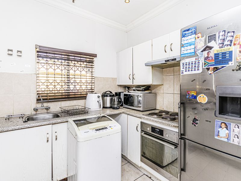 Compact kitchen featuring built-in cabinetry, granite countertops, integrated oven and hob, and tiled backsplash with functional layout.