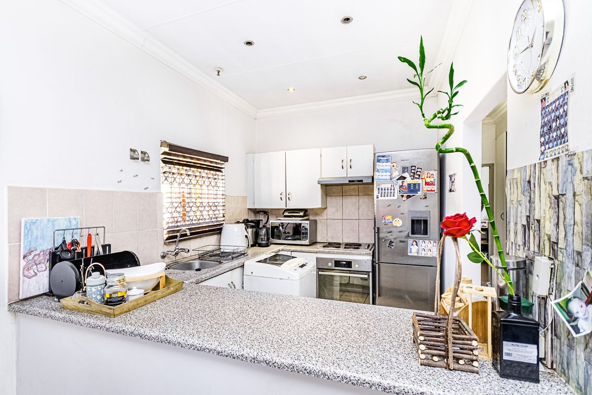 Compact kitchen featuring granite countertops, built-in cabinetry, stainless steel oven, hob, and extractor fan, with a functional breakfast bar layout.