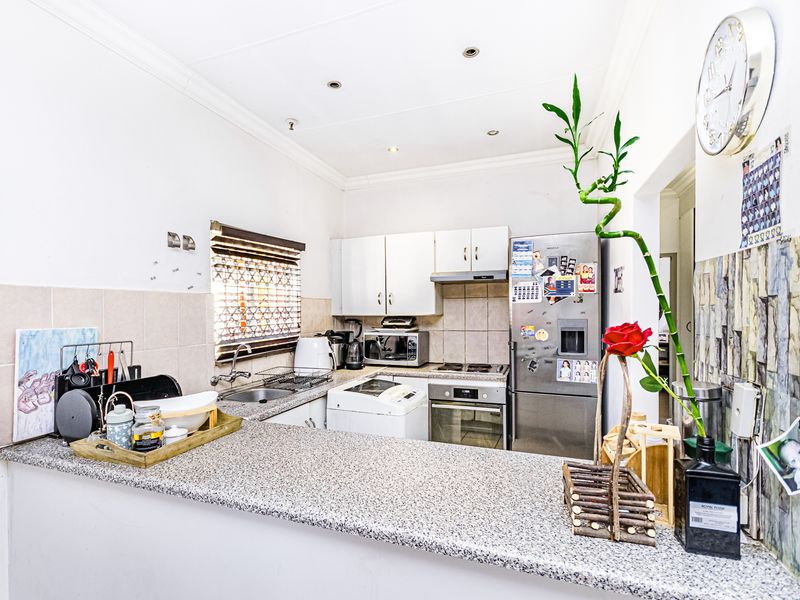 Compact kitchen featuring granite countertops, built-in cabinetry, stainless steel oven, hob, and extractor fan, with a functional breakfast bar layout.