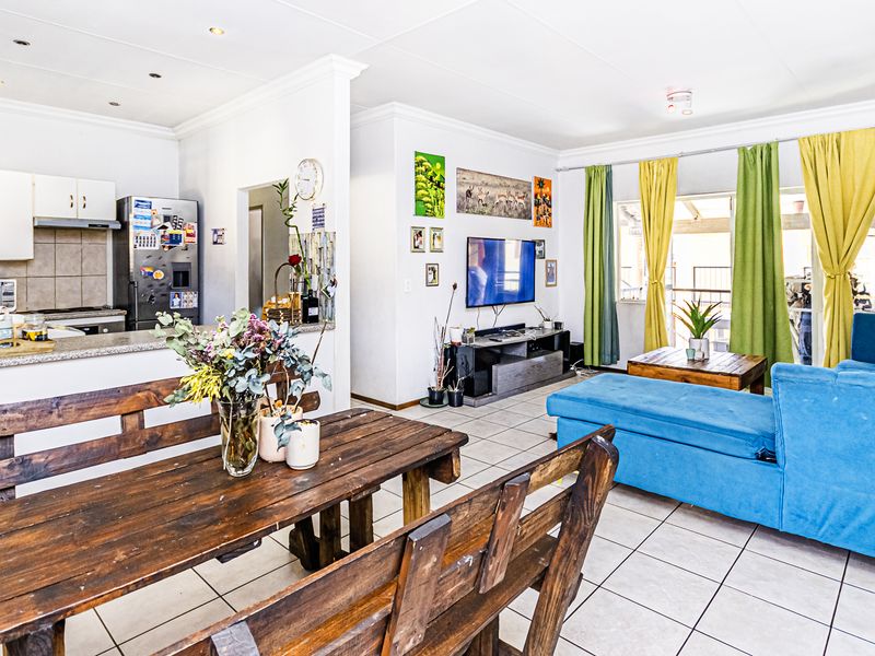 Open-plan living area featuring a kitchen with built-in cabinetry, tiled flooring throughout, and direct access to an outdoor patio area.