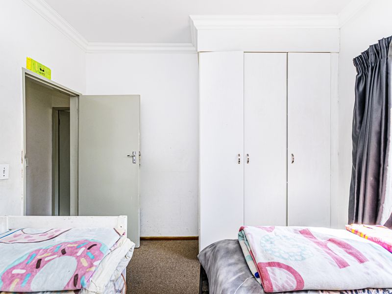 A bedroom featuring built-in cupboards, carpeted flooring, and decorative cornice detailing.