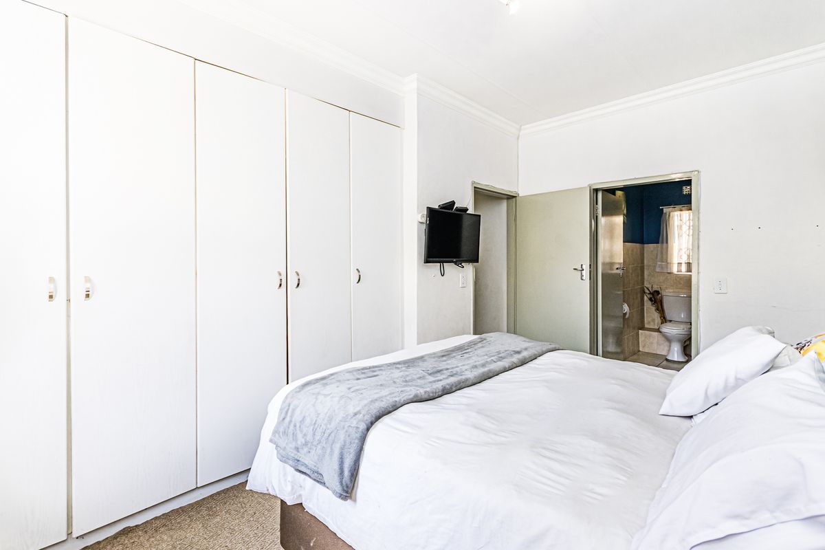 Bedroom featuring built-in cupboards, carpeted flooring, and direct access to an en-suite bathroom.