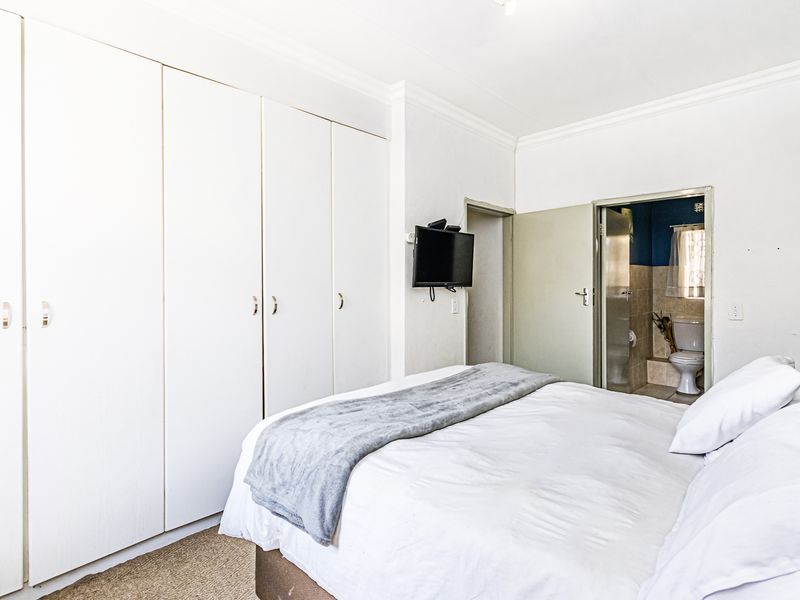 Bedroom featuring built-in cupboards, carpeted flooring, and direct access to an en-suite bathroom.
