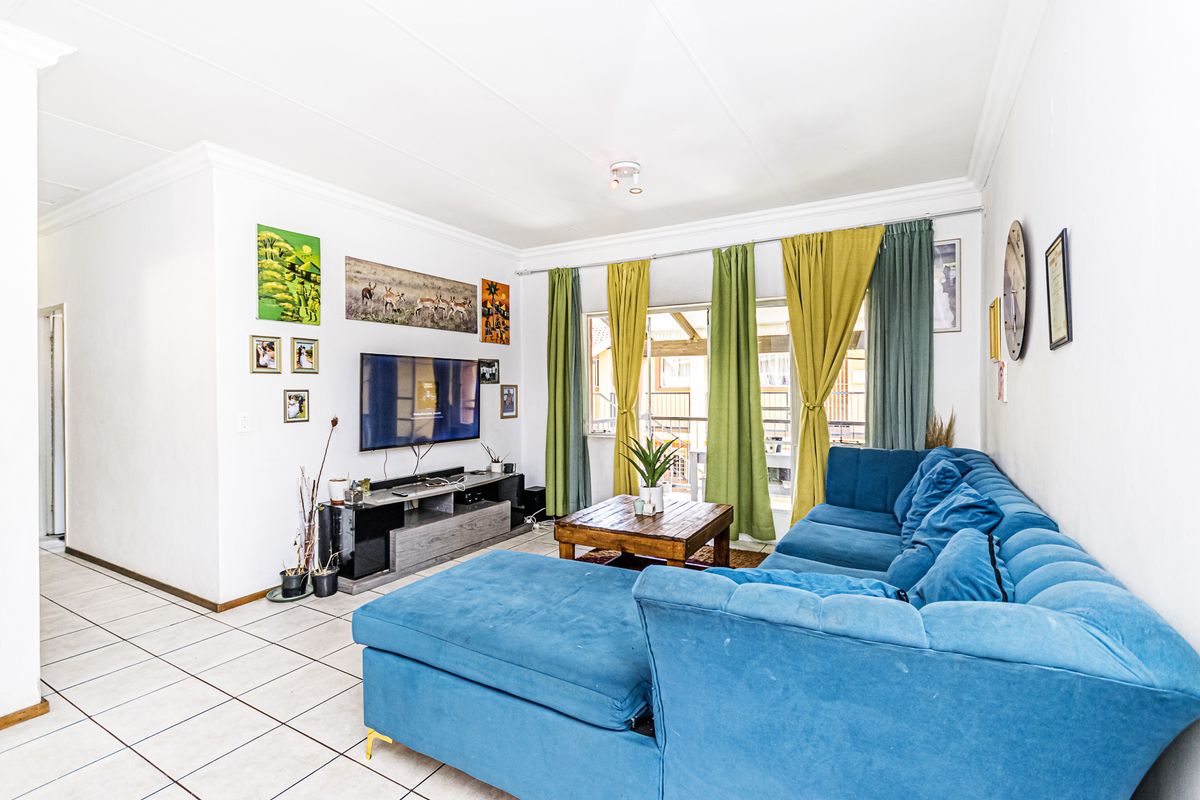 A bright living room featuring tiled flooring and a sliding glass door providing access to the outdoor area.