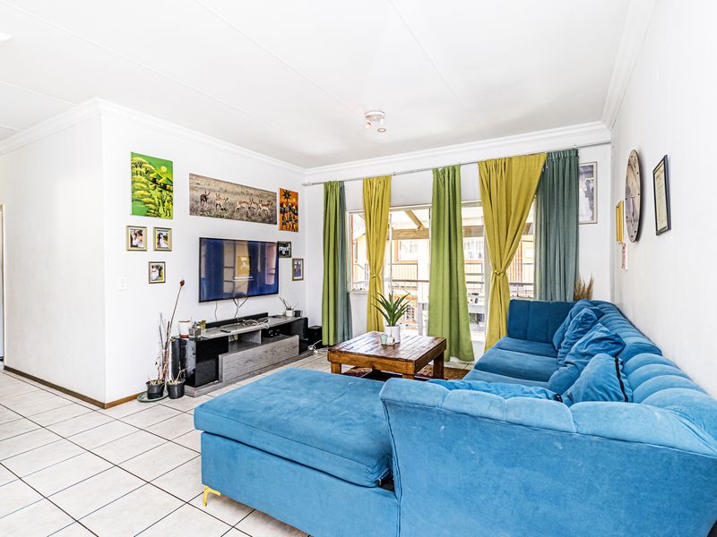 A bright living room featuring tiled flooring and a sliding glass door providing access to the outdoor area.