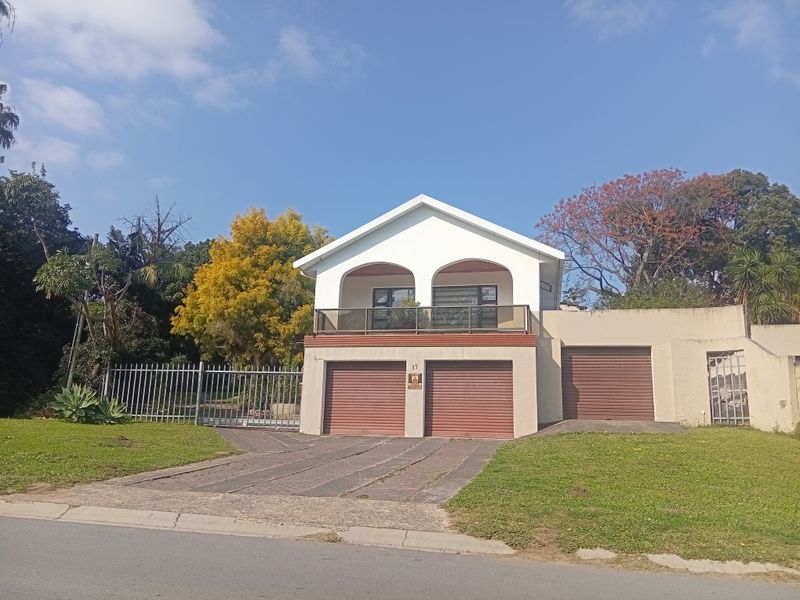 Front elevation of a residential property featuring a double garage, a single garage, and an upper-level balcony with a paved driveway and security fencing.