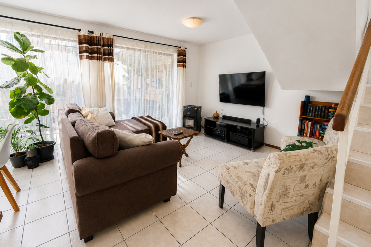 A bright living room featuring tiled flooring, a staircase, and large sliding glass doors that provide access to the outdoor area.