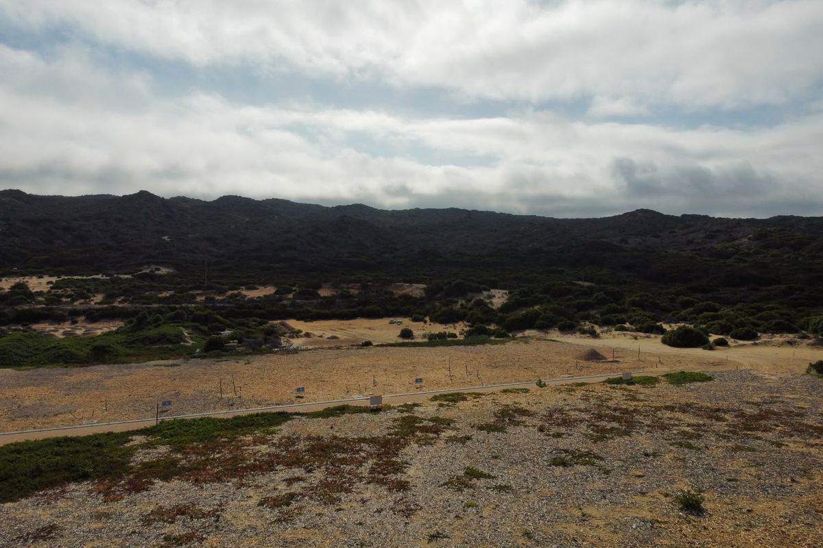 An aerial view of a large, undeveloped residential land plot featuring natural vegetation and surrounding mountain landscape.