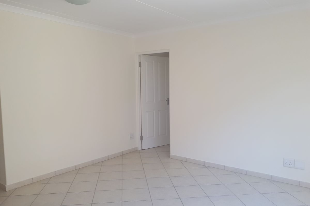 A bright, empty living area featuring neutral tiled flooring, coved ceilings, and a clean, minimalist aesthetic ready for personalization.