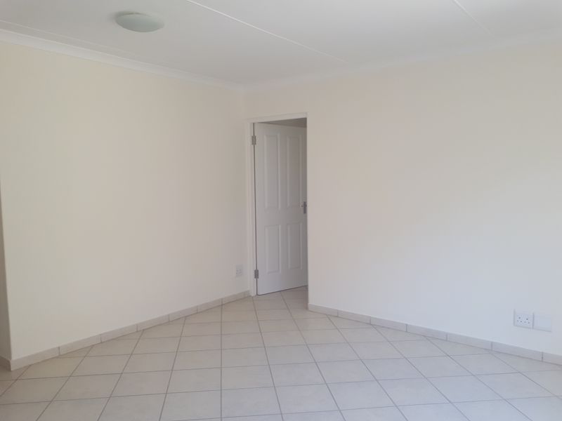 A bright, empty living area featuring neutral tiled flooring, coved ceilings, and a clean, minimalist aesthetic ready for personalization.