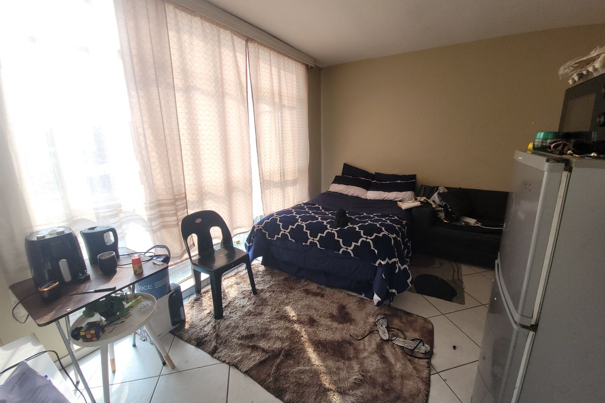 A bedroom featuring tiled flooring and a large sliding glass door that provides ample natural light.