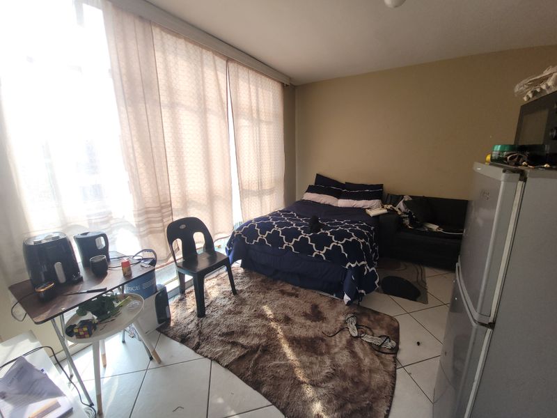 A bedroom featuring tiled flooring and a large sliding glass door that provides ample natural light.