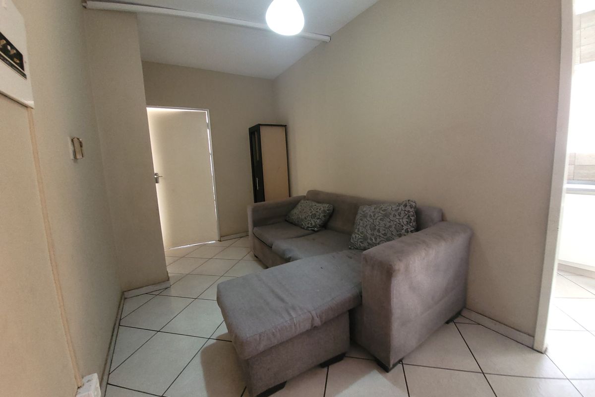 A compact living area featuring tiled flooring and neutral wall finishes, providing a functional space ready for modernization.
