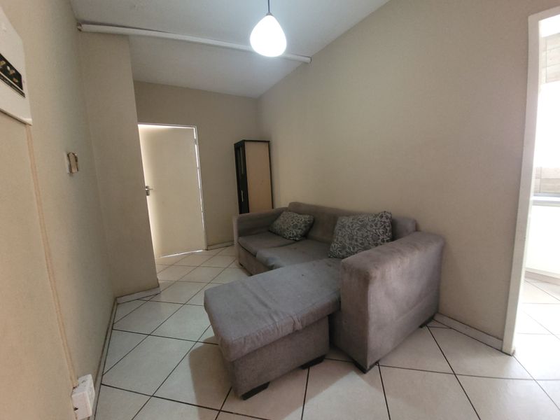 A compact living area featuring tiled flooring and neutral wall finishes, providing a functional space ready for modernization.