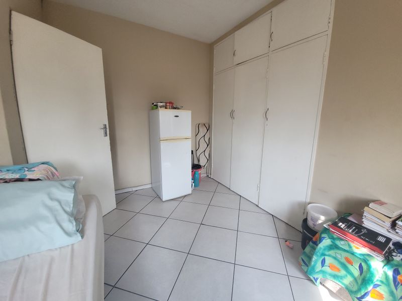 A bedroom featuring tiled flooring and built-in cupboards, offering functional storage space.