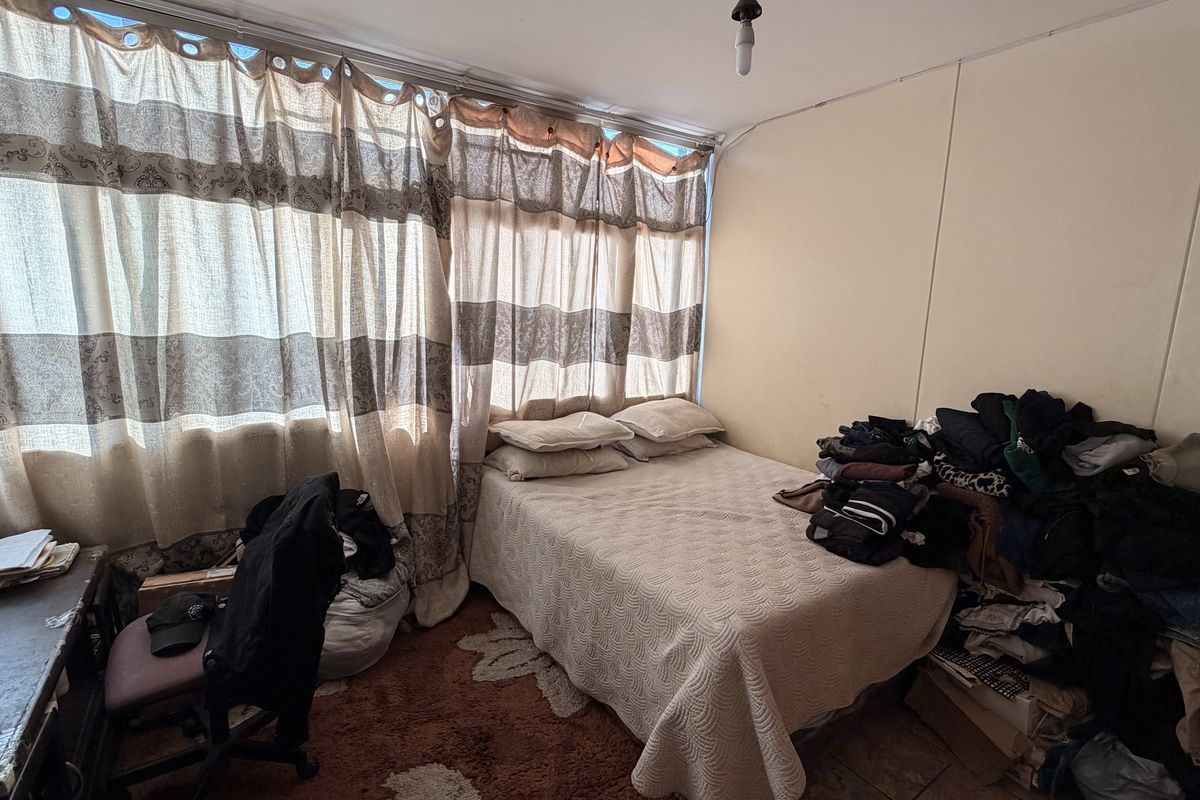 A bedroom featuring tiled flooring and large windows with curtains, requiring cosmetic updates to improve the overall condition of the wall and ceiling finishes.