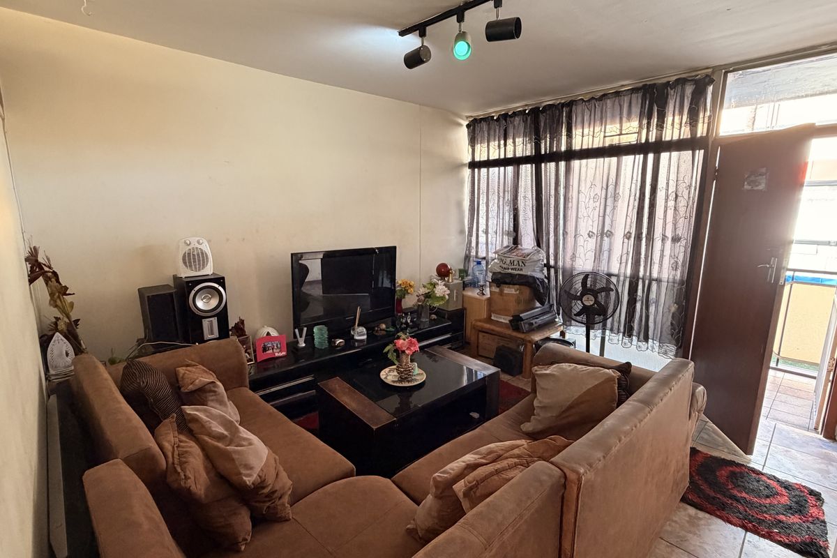 A living room area featuring tiled flooring, track lighting, and a sliding glass door leading to an outdoor space.
