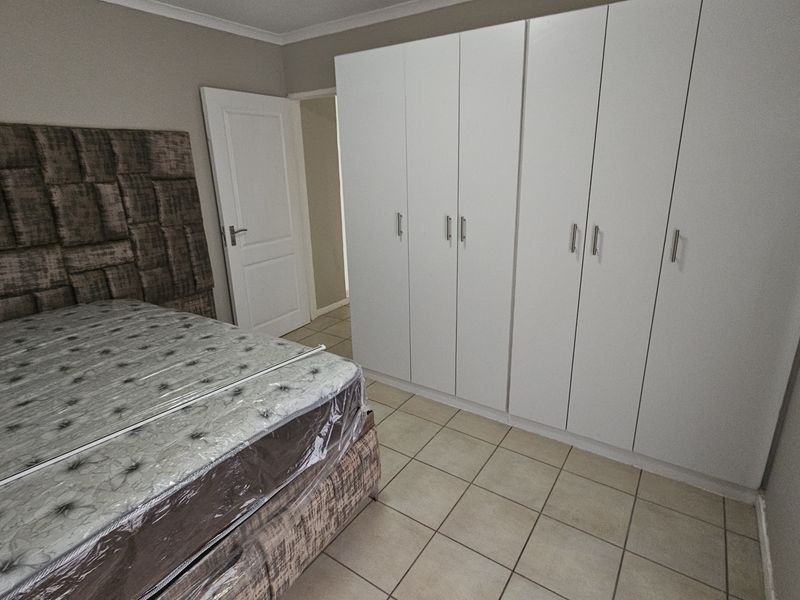 A bedroom featuring tiled flooring and extensive white built-in cupboards providing ample storage space.
