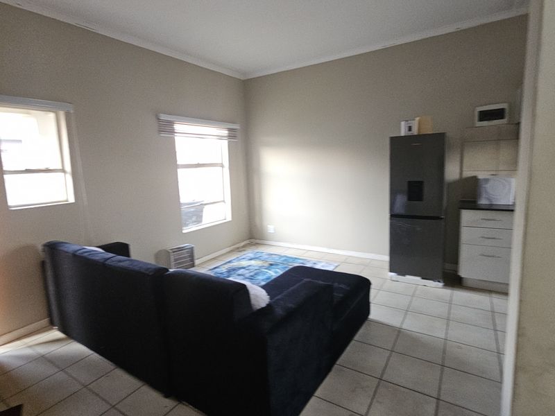 Open plan living area featuring tiled flooring and a compact kitchen section with built-in cabinetry and countertop space.