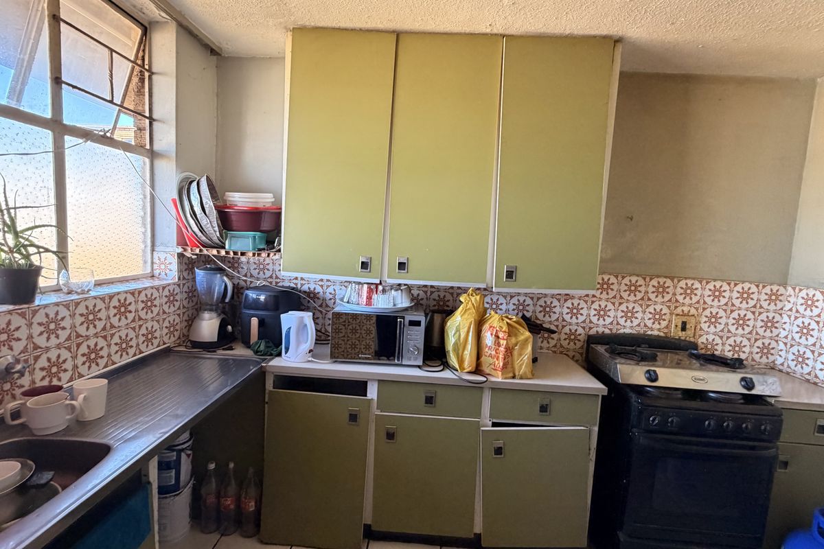 A dated kitchen featuring original cabinetry, a tiled backsplash, and a gas stove, offering significant potential for a modern renovation.
