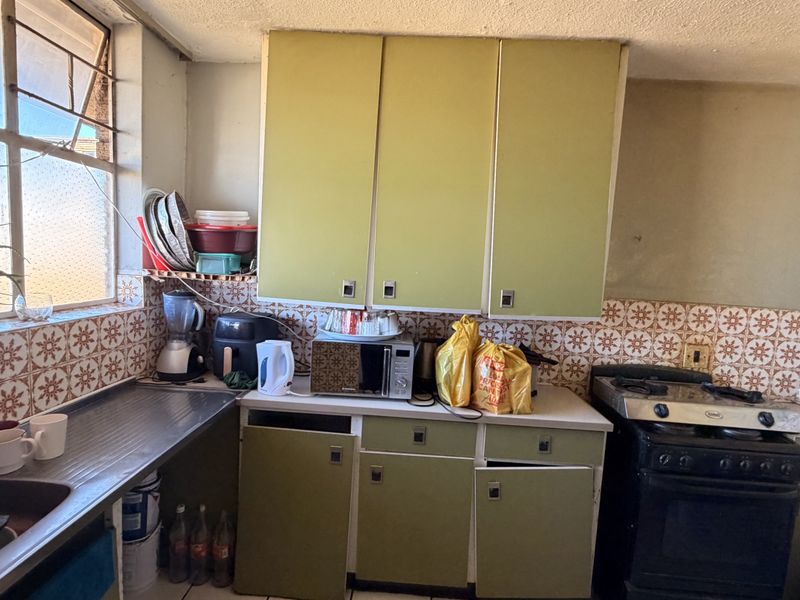 A dated kitchen featuring original cabinetry, a tiled backsplash, and a gas stove, offering significant potential for a modern renovation.