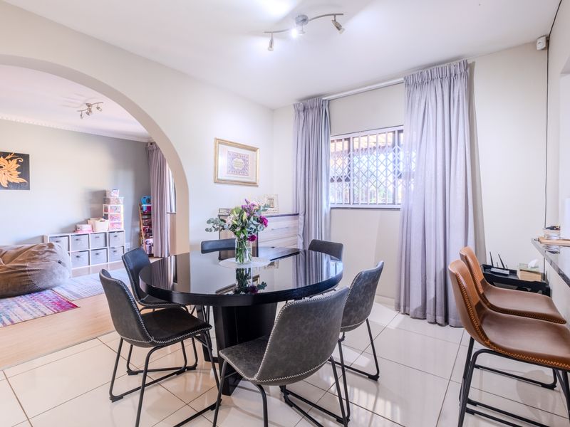 Open-plan dining area featuring tiled flooring, a breakfast bar, and an arched transition to the adjacent living space.