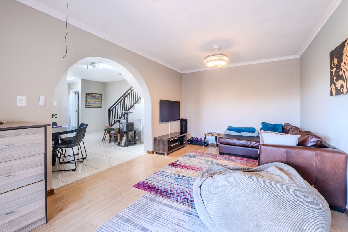 Spacious living area featuring laminate flooring, an elegant archway leading to the dining space, and a ceiling fan, creating a comfortable and open atmosphere.